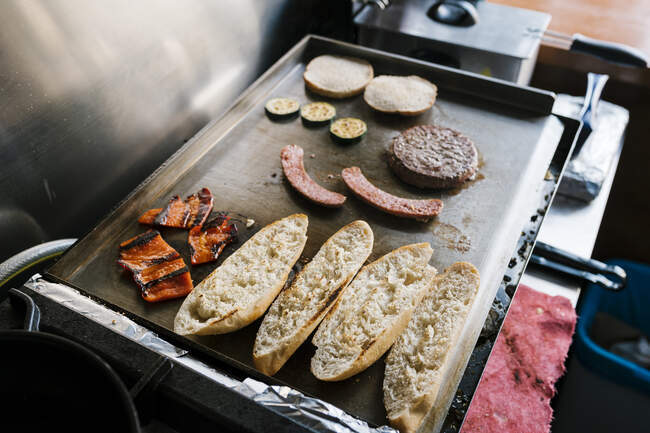 Hamburger ingredients on griddle of restaurant — Stock Photo