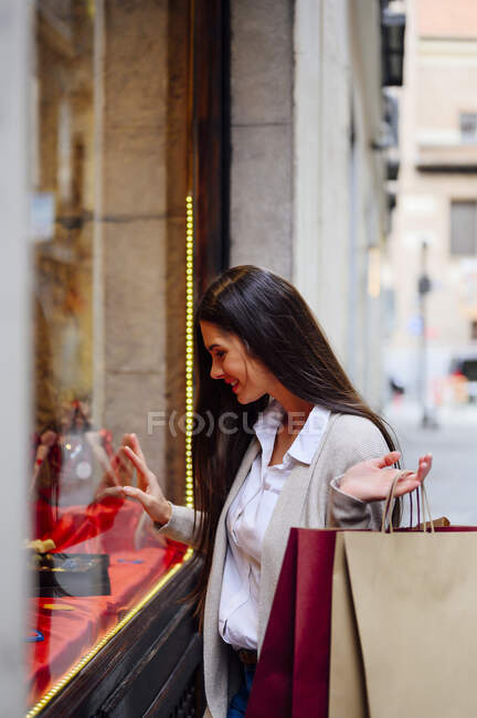 Mujer sonriente tocando el vidrio mientras compra ventana - foto de stock