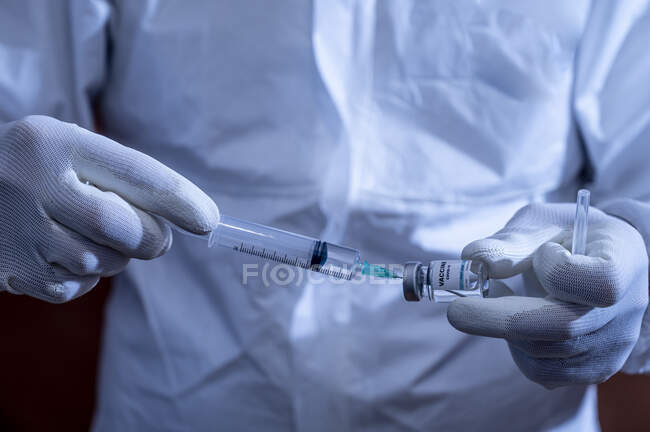 Mature man filling syringe through vial — Stock Photo