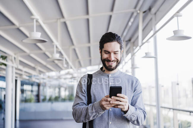 Rire hipster mâle avec téléphone portable assis sur les marches pendant la journée ensoleillée — Photo de stock