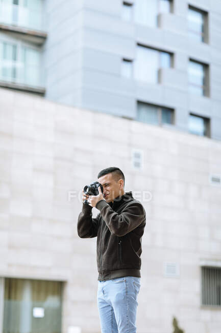 Junge männliche Profis fotografieren durch Kamera, während sie gegen Gebäude stehen — Stockfoto