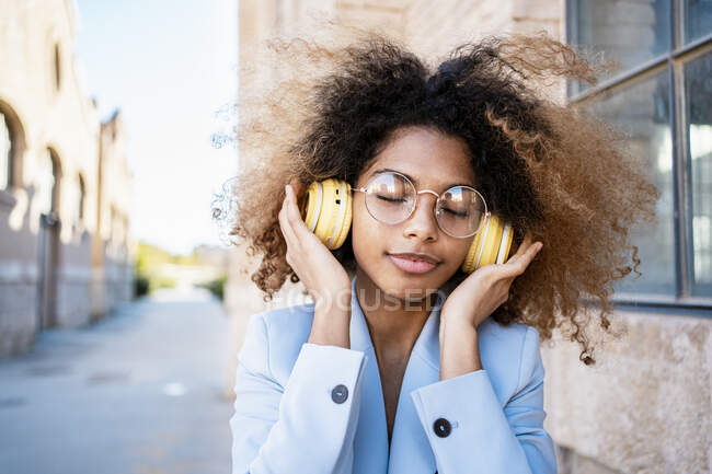 Afro donna con capelli castani ascoltare musica attraverso le cuffie — Foto stock