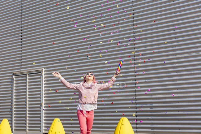 Glückliche Frau mit Party-Popper genießt Konfetti bei sonnigem Tag — Stockfoto