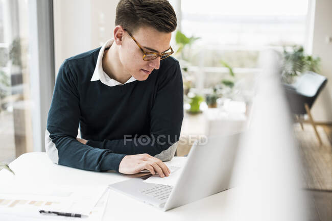 Geschäftsmann mit Brille liest Dokument während er am Schreibtisch sitzt — Stockfoto