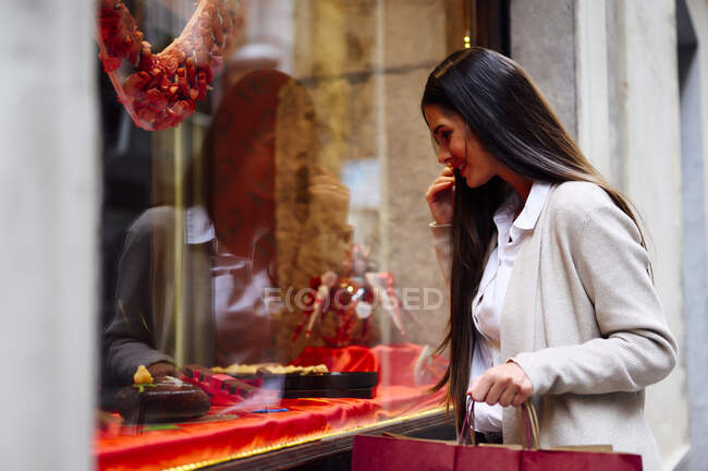 Woman window shopping while holding bags — Stock Photo