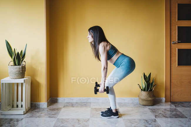 Atleta donna che si allena con i manubri a casa — Foto stock