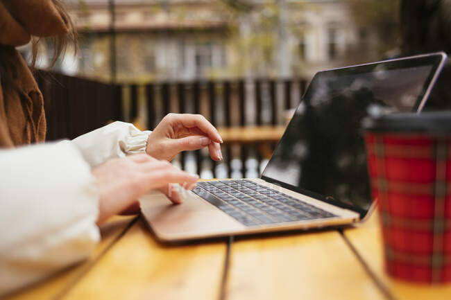 Femme utilisant un ordinateur portable tout en étant assis au café trottoir — Photo de stock