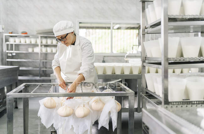 Sapiente chef femminile legare formaggio avvolto in vestiti su asta in magazzino — Foto stock