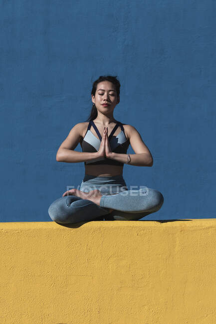 Donna con gambe incrociate meditando contro il muro — Foto stock