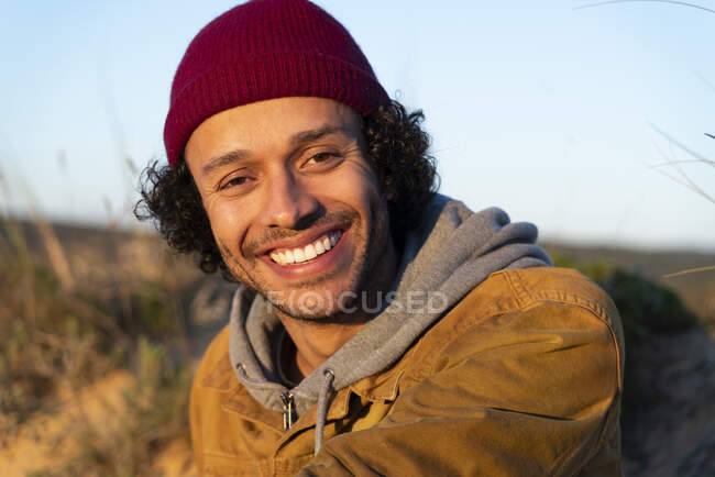 Junger Mann mit Strickmütze lächelt im Freien — Stockfoto