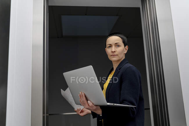 Unternehmerin hält Laptop im Büro am Türrahmen — Stockfoto