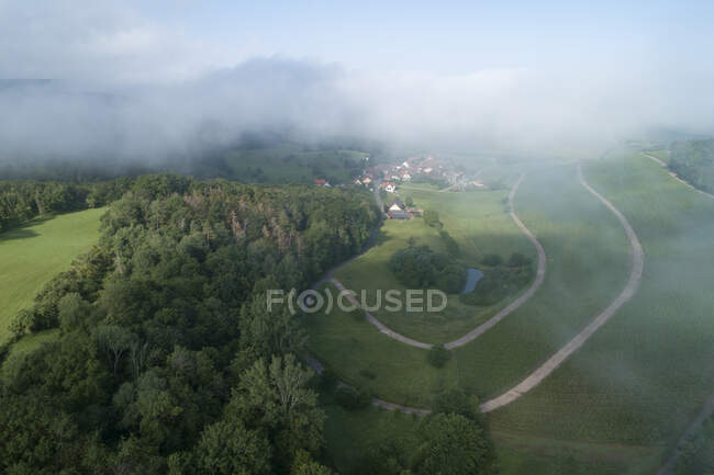 Vue par drone du brouillard matinal flottant au-dessus du village rural — Photo de stock
