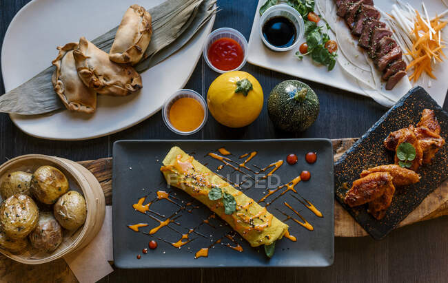 Cannelloni, pâtisseries, pommes de terre, viande et ailes servis au restaurant — Photo de stock