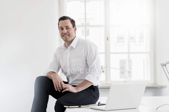Empresario sentado con portátil en el escritorio en la oficina - foto de stock