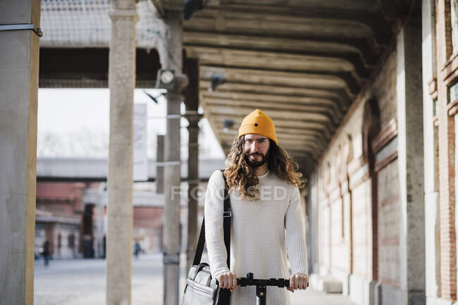 Male hipster with push scooter standing in corridor — long hair,  individuality - Stock Photo | #490889508