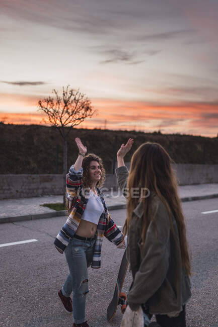 Lächelnde Freundinnen machen am Wochenende High-Five auf der Straße — Stockfoto