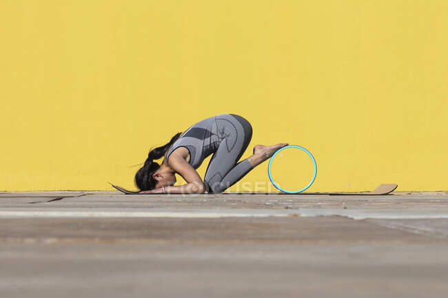 Donna che fa esercizio ruota yoga da parete gialla — Foto stock