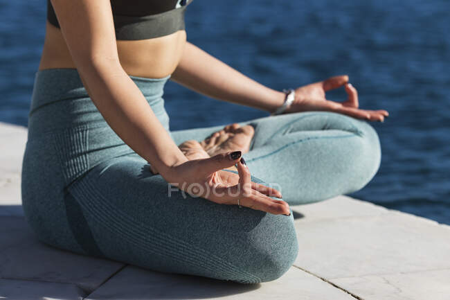 Sportlerin sitzt im Schneidersitz und übt Lotusposition auf Promenade — Stockfoto