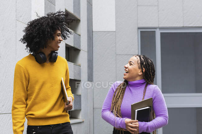 Lächelnde Studenten, die sich im Stehen an der Universität anschauen — Stockfoto