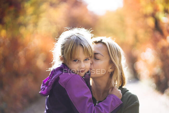 Мати цілує гарну доньку в щічку в парку. — стокове фото