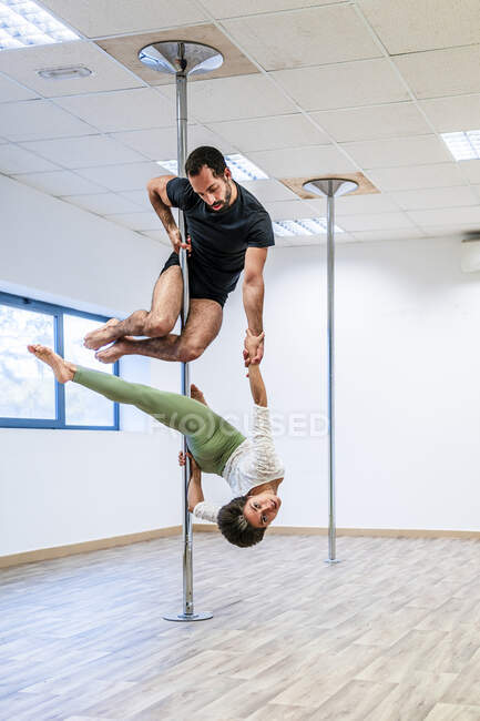 Acrobati multietnici maschili e femminili che si esercitano insieme su asta in studio di danza — Foto stock