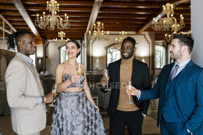 Eleganti uomini e donne che tengono flauto champagne al banchetto — Foto stock