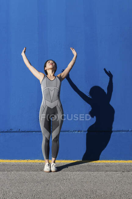 Femme exerçant contre le mur bleu — Photo de stock