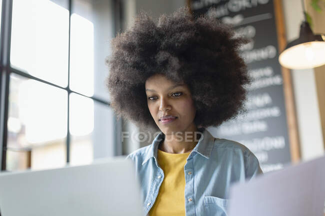Femme d'affaires afro regardant un ordinateur portable dans un café — Photo de stock