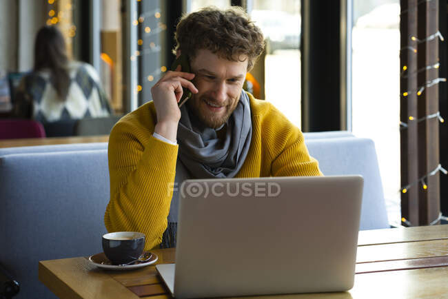 Schöner Geschäftsmann telefoniert im Café mit Laptop — Stockfoto