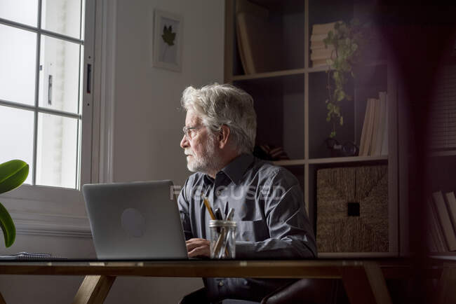 Thoughtful senior professional looking away at home — Stock Photo