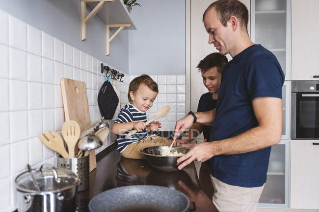 Padre con figli carini preparare il cibo in cucina a casa — Foto stock