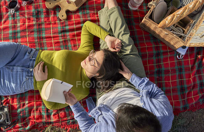 Uomo lettura libro mentre fidanzata sdraiato in grembo durante la giornata di sole — Foto stock