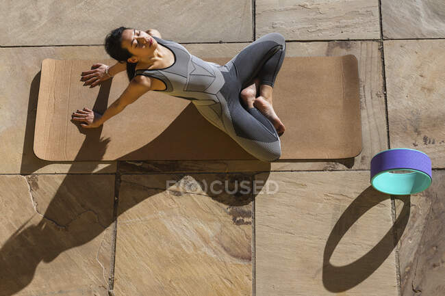 Sportswoman fare esercizio di rilassamento sul tappeto sul lungomare — Foto stock