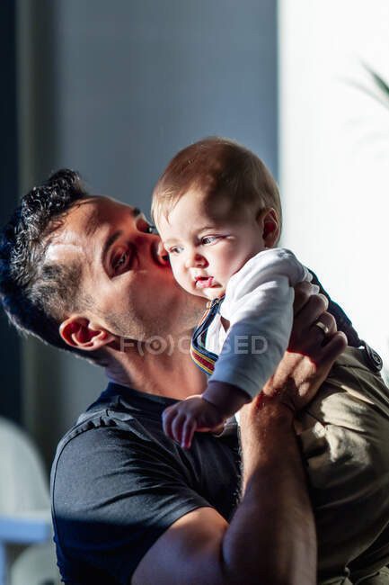 Uomo baciare bambino ragazzo mentre in piedi a casa — Foto stock