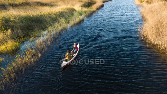 Casal jovem viajando através de canoa no rio na floresta — Fotografia de Stock