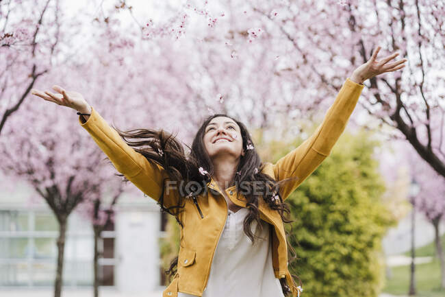 Insouciant mi-adulte femme jetant des fleurs pendant le printemps — Photo de stock