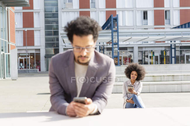 Entrepreneurs masculins et féminins utilisant le téléphone intelligent pendant la journée ensoleillée — Photo de stock