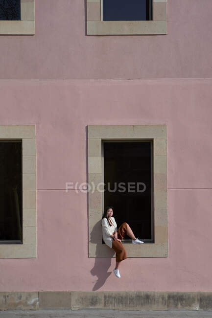 Asiatico donna seduta su finestra davanzale di costruzione durante sole giorno — Foto stock