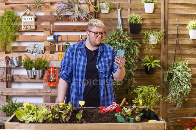 Giovane utilizzando smartphone nel suo giardino urbano — Foto stock