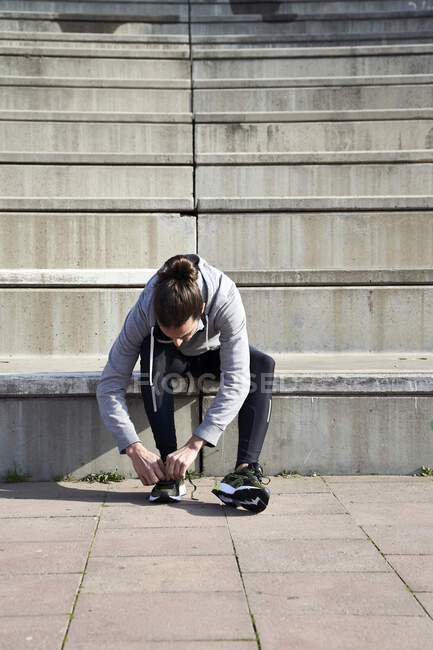 Man tying shoelace while sitting on steps — Stock Photo