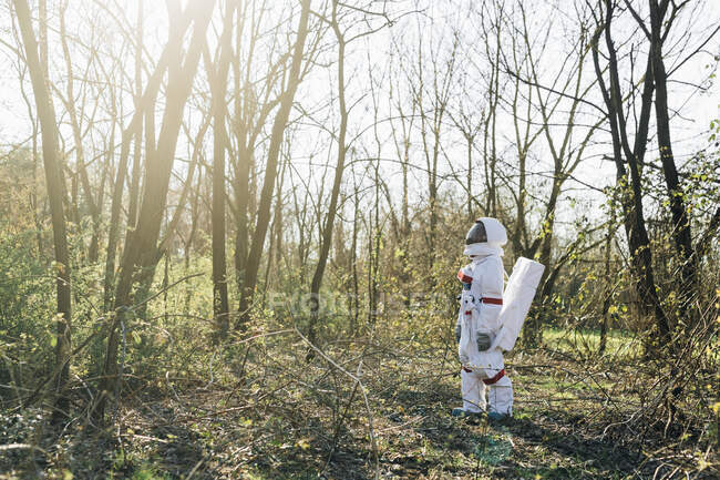 Young astronaut searching in forest on sunny day - foto de stock