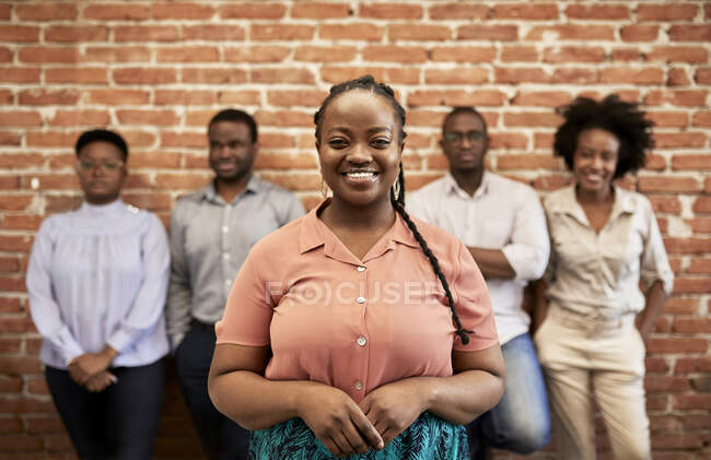 Imprenditrice sorridente con colleghi in background in ufficio — Foto stock