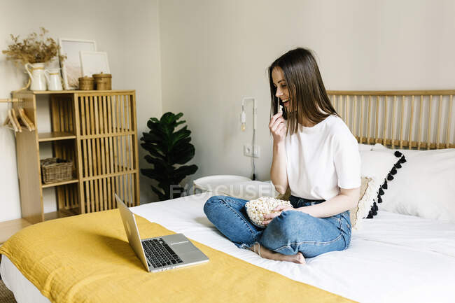 Frau isst Popcorn, während sie zu Hause auf Laptop schaut — Stockfoto