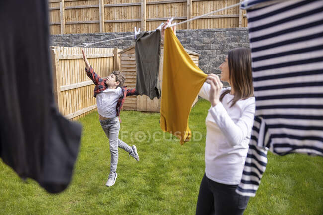 Madre guardando ragazzo toccare clothesline mentre salta su erba nel cortile posteriore — Foto stock
