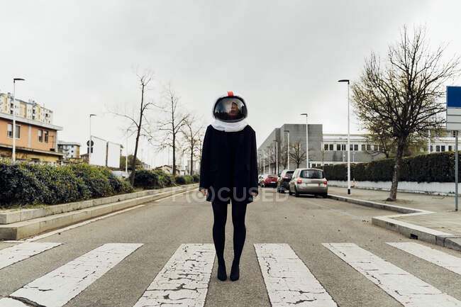 Mujer con casco espacial de pie en zebra cruzando en la calle - foto de stock