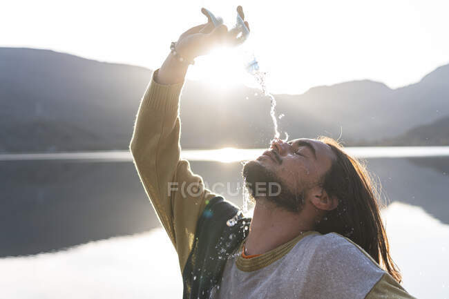 L'uomo versa acqua sul viso durante la giornata di sole — Foto stock