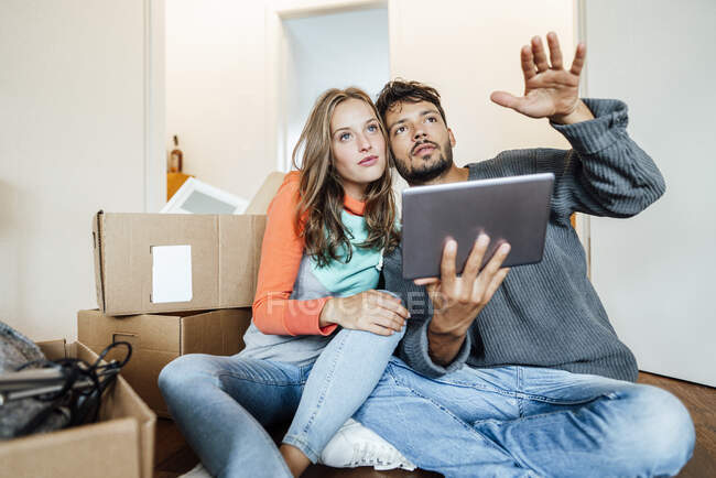 Jovem casal sentado com planejamento tablet digital em casa — Fotografia de Stock