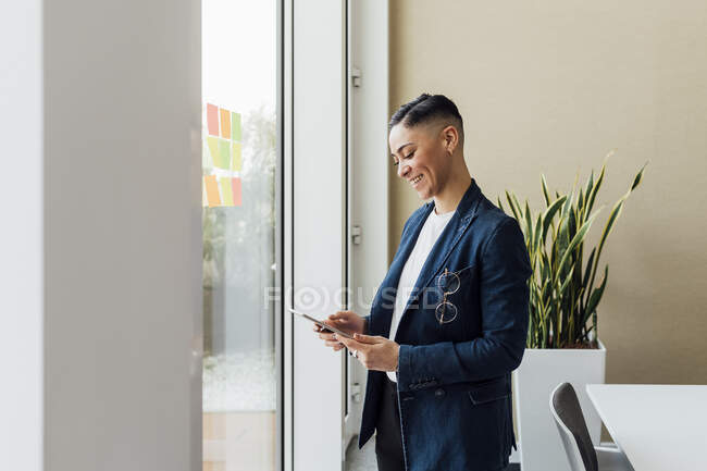 Посміхаючись підприємець за допомогою цифрового планшета по офісі — стокове фото