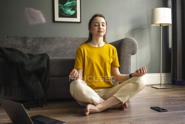 Молодая женщина медитирует, сидя дома — стоковое фото