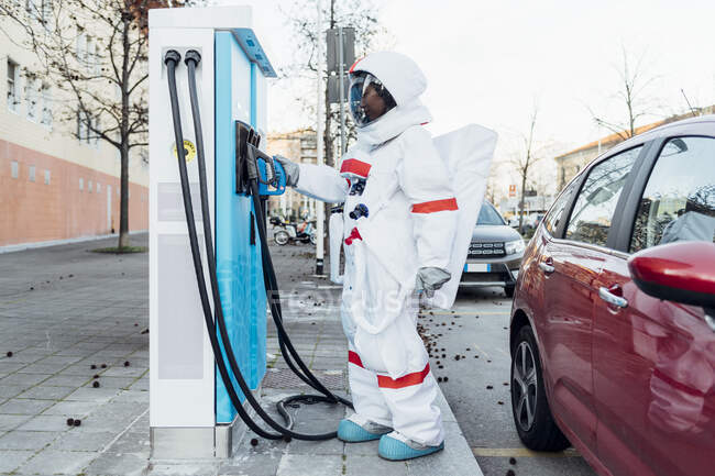 Female astronaut standing at fuel station in city — Stock Photo